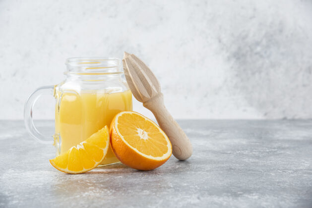 异国情调石桌上放着一杯果汁和新鲜的橙子果汁圆形橙子