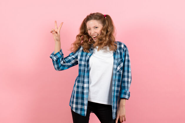 肖像前视年轻女性穿着蓝色格子衬衫 在粉色背景上表达快乐女性情感模特时尚女孩的色彩漂亮情感表情