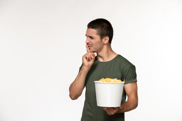 电影正面图身穿绿色t恤的年轻男性手持篮子 白色墙上有cips电影男性孤独电影电影院电影年轻的男性篮子