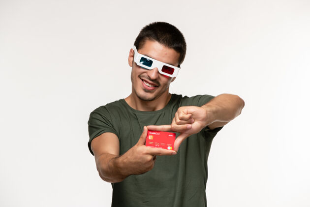 男人正面图身着绿色t恤 戴着d墨镜 拿着银行卡的年轻男子在白墙电影《孤独电影院》中微笑电影肖像电影