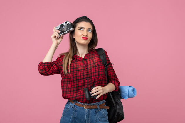 肖像前视图年轻女性用望远镜和相机对一个粉红色背景色的女人人类相机微笑漂亮