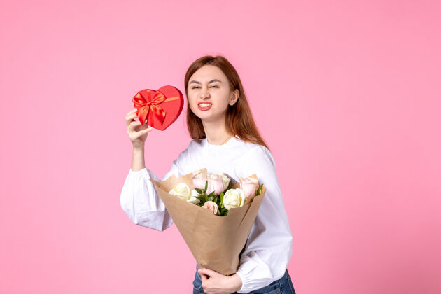 年轻女性正面图：年轻女性 带鲜花 作为妇女节礼物 粉色背景 水平三月 女性平等 爱情 性感的日期 玫瑰花束礼物礼物