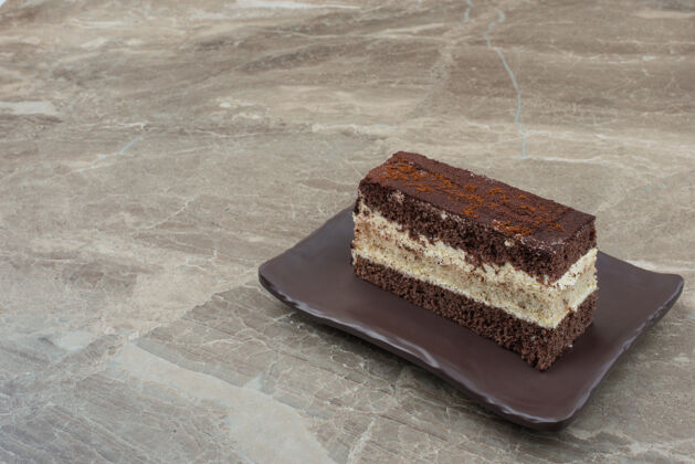 蛋糕把一片巧克力蛋糕放在黑盘子里糕点巧克力盘子