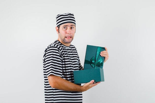 模特年轻男子拿着打开的礼盒 穿着t恤 戴着帽子 神情迷茫脸困惑胡子