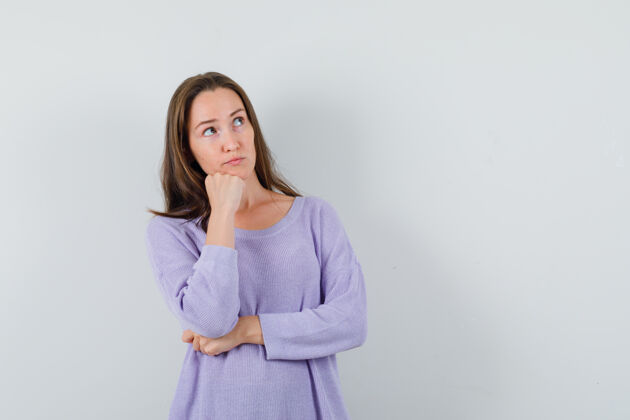 旁白年轻的女性穿着淡紫色的衬衫向旁边望去 看上去很体贴前视图卷发姿势衬衫