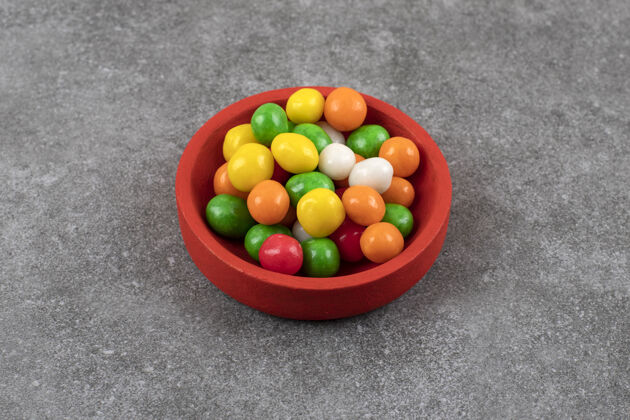 可口石头桌上放着一碗五颜六色的圆形糖果各色糖果鹅卵石