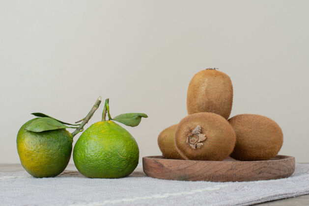 桌布在灰色桌布上放上奇异果和新鲜橘子天然新鲜成熟
