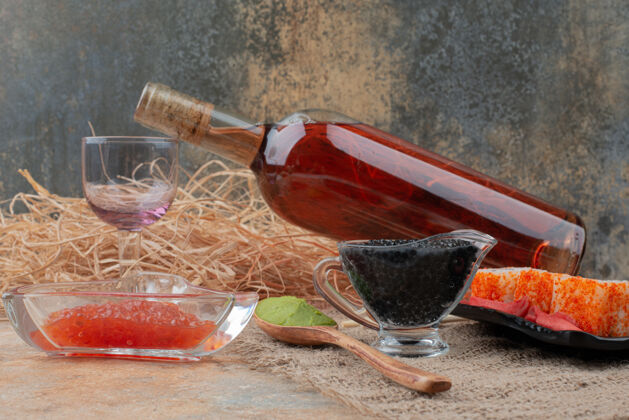 瓶子一瓶葡萄酒 酒杯和寿司放在粗麻布上酒精深色鱼子酱