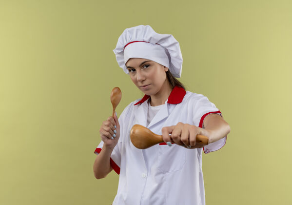 厨师年轻自信的白人厨师女孩穿着厨师制服 拿着勺子放在绿色的空间里烹饪空间汤匙