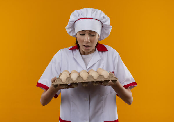 厨师穿着厨师制服的年轻白人厨师女孩抱着一堆鸡蛋 看着放在橘子上的鸡蛋 并留着复印空间空间鸡蛋制服