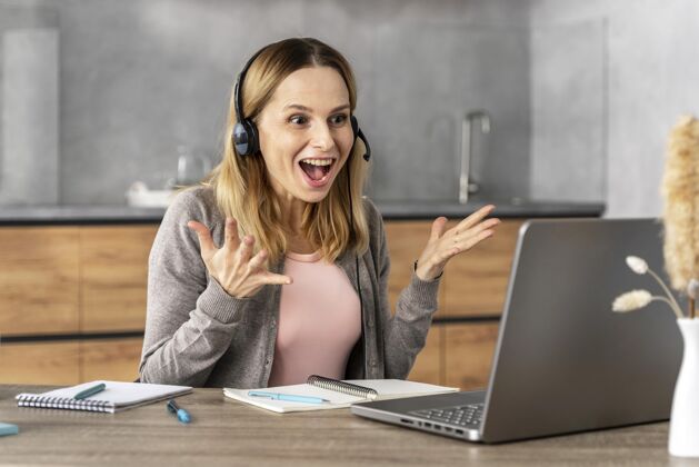 女性戴着耳机在笔记本电脑上工作的女人学生耳机设备