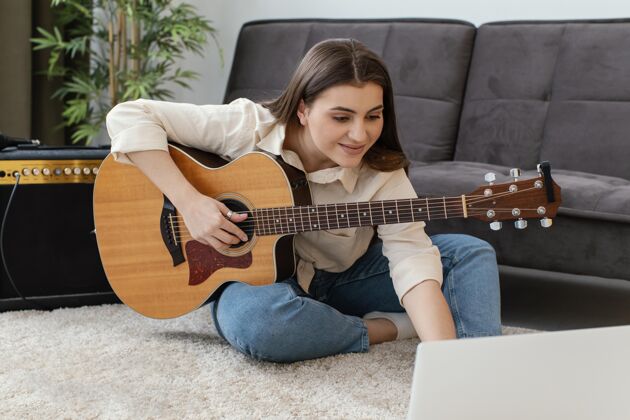 吉他带原声吉他和笔记本电脑的女音乐家艺术家房子家用