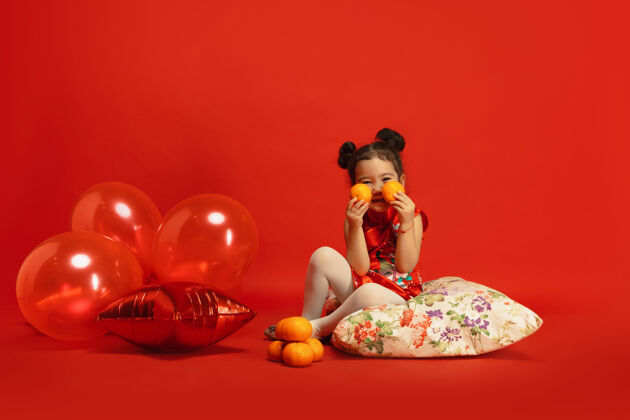 中文气球和普通话的心情摆可爱的姿势亚洲可爱的小女孩隔离在传统服装的红墙庆祝活动 人类的情感 节日复制空间美丽文化祝福