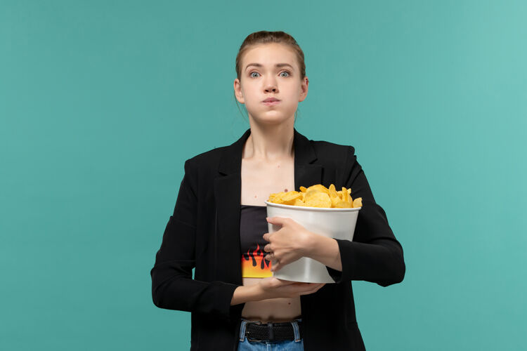 女正面图：年轻女性在蓝色桌子上吃薯片看电影土豆办公室办公桌