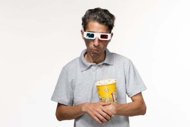 偏远正面图年轻男性戴着d型太阳镜在白色表面吃爆米花男孤独爆米花
