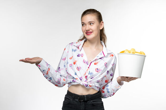 年轻的女性正面图：年轻的女性拿着篮子和薯片 在白色的表面上和某人说话抱着电影电影