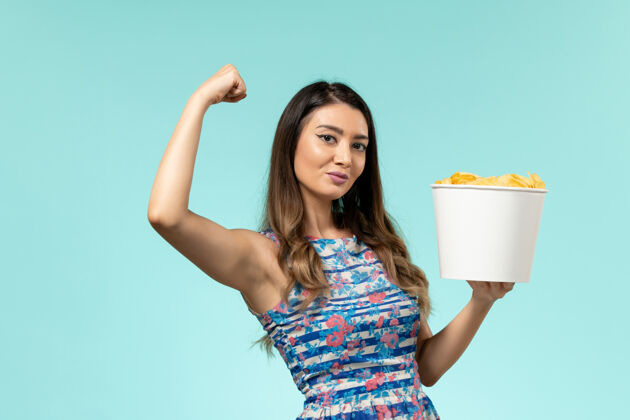 性感前视图年轻的女性拿着土豆片和蓝色表面弯曲篮子抱着前面年轻的女性