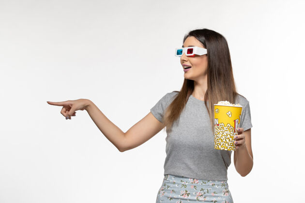 漂亮正面图年轻女性手持爆米花 戴着d墨镜在白色表面看电影年轻的女性前面太阳镜