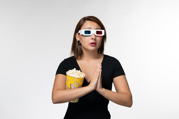 电影正面图：戴着d型太阳镜手持爆米花的年轻女性在白色表面祈祷性感太阳镜电影院