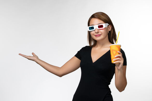 女正面图：戴着d墨镜拿着苏打水的年轻女性站在白色的表面上电影孤独电影院