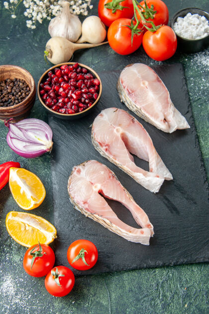 西红柿顶视图新鲜鱼片和红色西红柿放在深色的桌子上海鲜海洋肉类海餐胡椒菜沙拉水景观海鲜晚餐