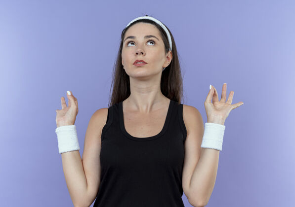 制造戴着头巾的年轻健身女士抬起头 用手指站在蓝色的墙上做冥想的姿势头带冥想女人