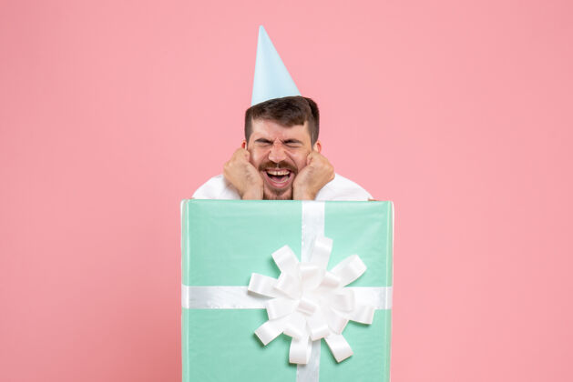 年轻男性正面图年轻男性站在礼物盒内浅粉色圣诞照片情感睡衣派对灯正面展台