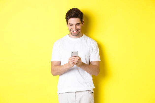 自信年轻人在智能手机上看短信 看着手机屏幕微笑着 站着模特男人成年人