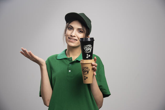 咖啡穿着绿色制服拿着咖啡杯的女送货员女孩女性职业