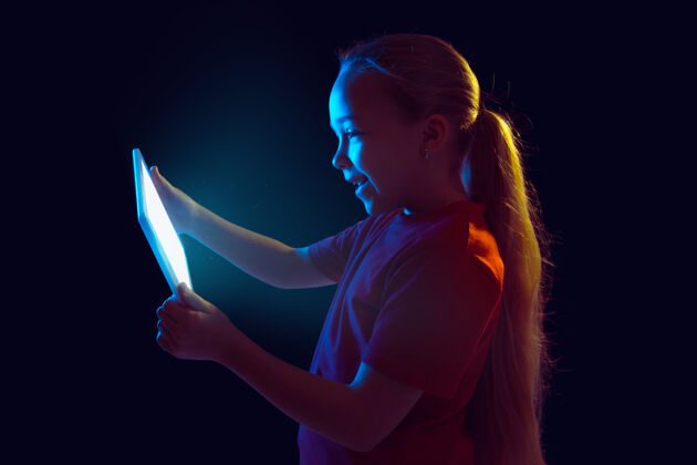 在线霓虹灯下拿着平板电脑的小女孩表演手势手