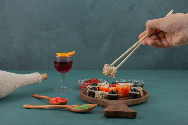 酒女人用筷子和一杯酒手拿寿司手酱油食物