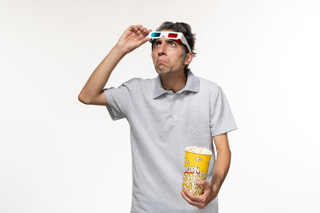 太阳镜正面图：年轻男性戴着d型太阳镜在白色表面上吃爆米花看电影年轻的男电影看