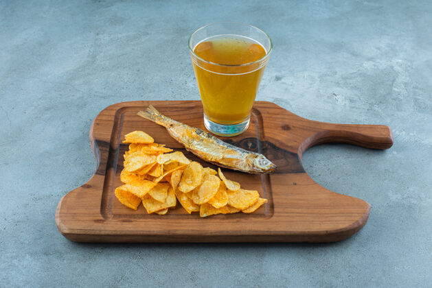 垃圾薯条 鱼和一杯啤酒放在木板上 大理石背景上美味美味啤酒