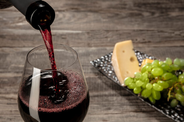 玻璃杯木桌上放着一瓶红酒和一杯水果小吃切片文化