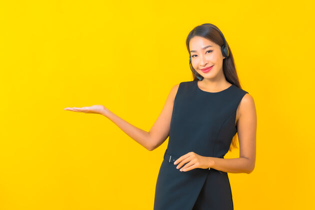 工人肖像美丽的年轻亚洲女商人与耳机呼叫中心客户关怀黄色背景呼叫咨询护理