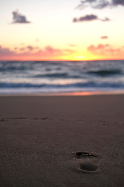 海洋沙滩上的人类足迹在夕阳下闪闪发光人类太阳海滩