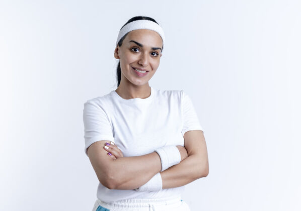 微笑年轻微笑的白人运动女性戴着头带和腕带交叉双臂站在白色空间与复制空间隔离手臂年轻穿