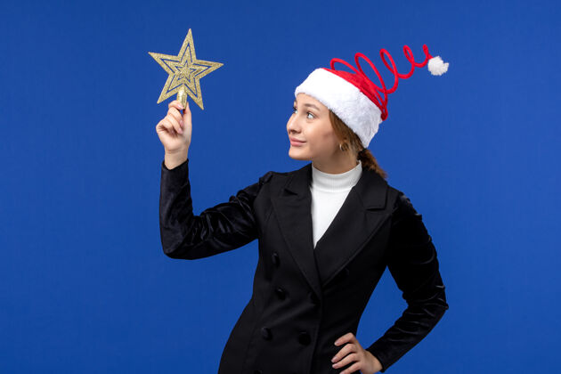 商人正面图年轻女性手持蓝色墙壁上的星形装饰新年假期圣诞节行政圣诞节景观