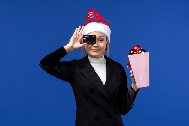 情绪前视图：带着圣诞树玩具和银行卡的年轻女士在蓝色墙壁上欢度新年职业银行帅哥