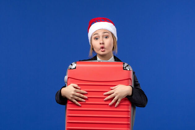 圣诞节正面图年轻女子提着沉重的红包在蓝墙度假女子度假包年轻女性成人