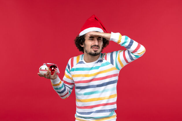 男正面图年轻人手持圣诞树玩具红墙假日红人新年活跃圣诞节球员