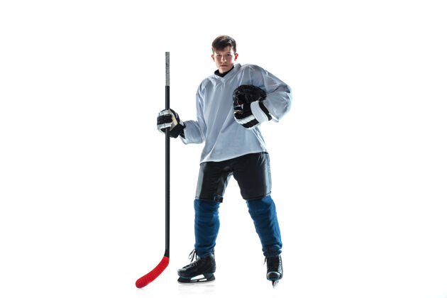 冰得分冰球场上有棍子和白色背景的年轻男子冰球运动员运动员穿着装备和头盔练习运动概念 健康的生活方式 运动 运动 动作动作运动员动作