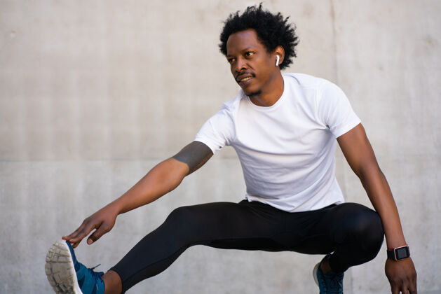 运动非裔运动男伸展双腿 在户外运动前热身运动和健康的生活方式理念成人休闲锻炼