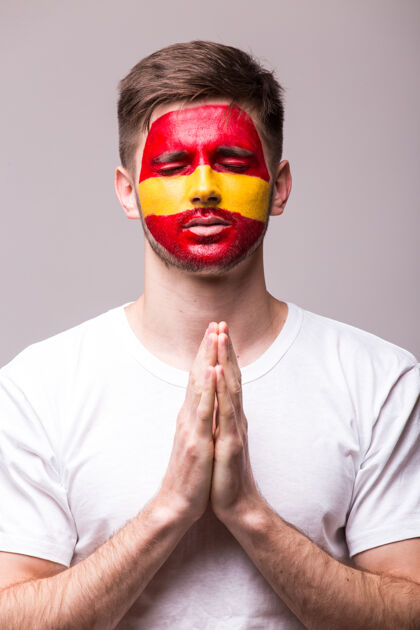 运动年轻的西班牙男足球迷用祈祷的手势孤立在白墙上体育足球欢乐