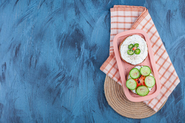 芝麻切好的蔬菜放在奶酪面包上 放在毛巾上 放在三角架上 放在蓝色的板上美味开胃菜美味