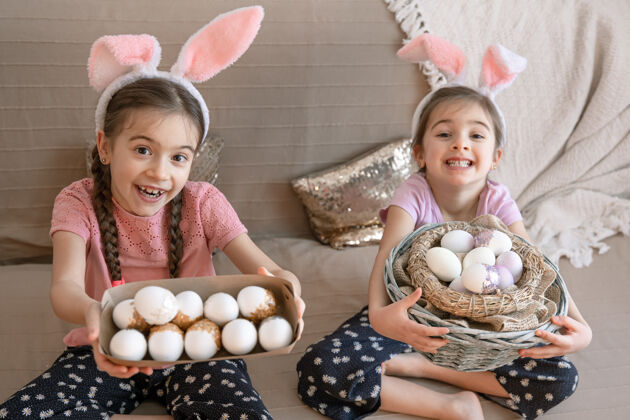 姿势有兔子耳朵的快乐小姐妹们 还有复活节彩蛋庆祝复活节孩子