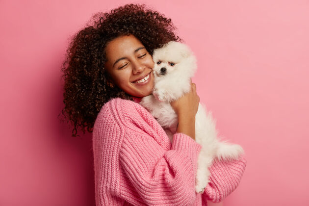 小少数民族妇女用快乐和爱拥抱白狗 温柔地微笑 享受与最喜爱的宠物在一起 有友好的关系 为狗展做准备动物姿势宠物