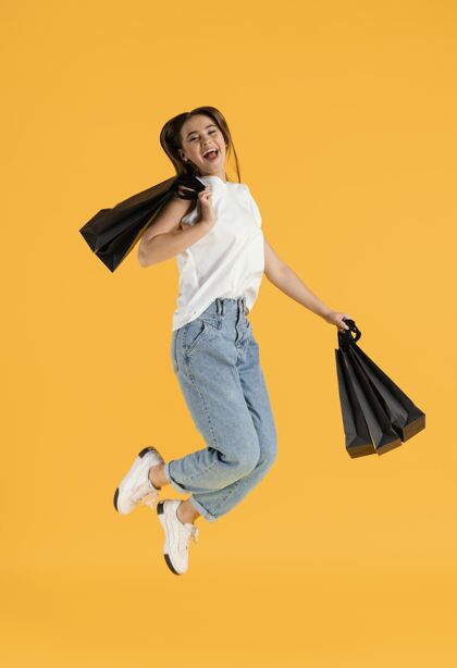 女人带着购物袋跳跃的年轻女性肖像跳跃肖像美丽