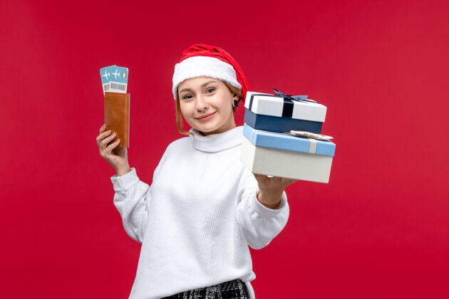 飞机正面图：带着礼物和机票的年轻女子在红地板飞机上度过圣诞新年票帽子礼物