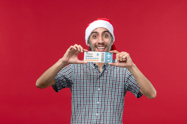 脸正面图红色背景下手持机票的年轻男性圣诞节人抱着